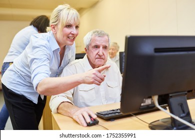 El profesor explica a un adulto mayor cómo trabajar en un PC y en Internet en un curso de informática