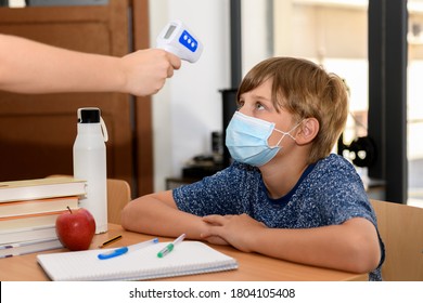 Teacher with facemask scanning a kid with digital thermometer, measuring body temperature before lessons. New normal, back to school during coronavirus pandemic. - Powered by Shutterstock