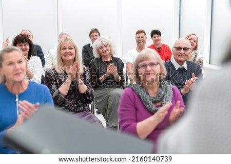 teacher with a folder in his hand teaches elderly people busines