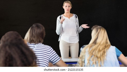 Teacher Gesturing While Explaining Adult Male And Female Students Against Black Background. Education, Knowledge And Mentorship.