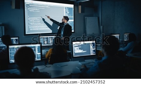 Teacher Giving Computer Science Lecture to Diverse Multiethnic Group of Female and Male Students in Dark College Room. Projecting Slideshow with Programming Code. Explaining Information Technology.