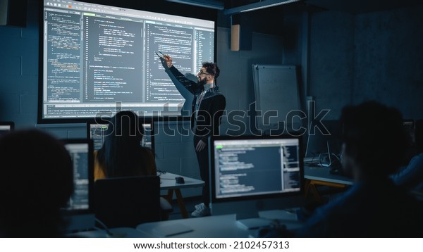 Teacher Giving Computer Science Lecture to\
Diverse Multiethnic Group of Female and Male Students in Dark\
College Room. Projecting Slideshow with Programming Code.\
Explaining Information\
Technology.