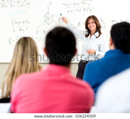 Teacher giving a lecture in a classroom and writing math formulas on the board