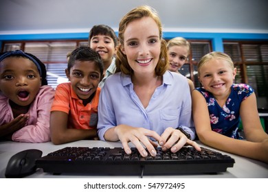 Teacher Giving Lesson To Her Students With Technology At School