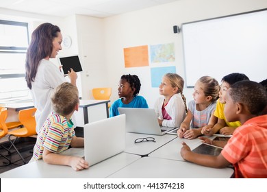 A teacher giving lesson with technology in classroom
