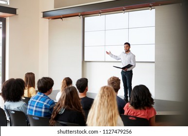 Teacher Giving Presentation To High School Class In Front Of Screen