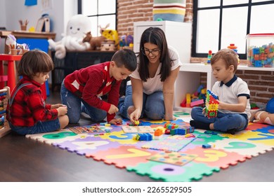 Teacher with group of boys playing with maths puzzle game sitting on floor at kindergarten - Powered by Shutterstock