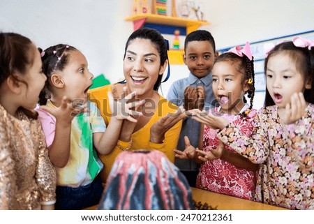 Teacher and group of children learning about volcanos at science kindergarten project. Multiracial kids studying at elementary school. Education concept