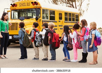 Teacher And A Group Of Elementary School Kids At A Bus Stop