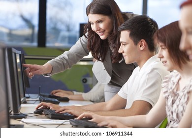 Teacher & group of male and female students using computers at a college