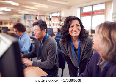 Teacher With Group Of Mature Adult Students In Class Working At Computers In College Library