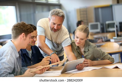Teacher with group of students working on digital tablet - Powered by Shutterstock