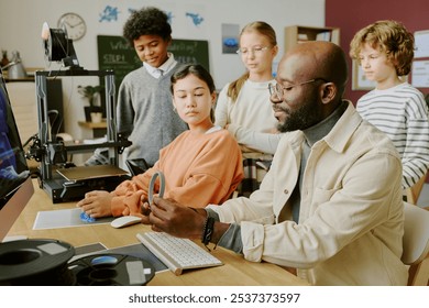 Teacher guiding diverse middle school students during hands-on classroom activity involving technology, fostering interactive learning and teamwork - Powered by Shutterstock