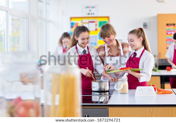 Teacher guiding her students while they cooks\
during a home economics\
class.