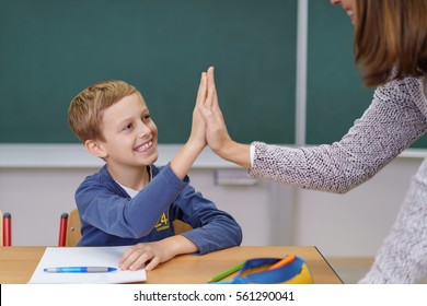 Teacher and happy grinning young student doing a high fives as the schoolboy finally succeeds in understanding something - Powered by Shutterstock