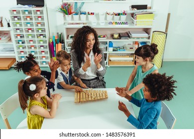 Teacher helping cheerful children playing some musical toys at kindergarten - Powered by Shutterstock