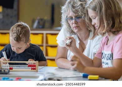 A teacher is helping a child with a math problem. The teacher is reviewing the students work in the classroom setting. - Powered by Shutterstock