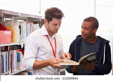 Teacher Helping College Student With Studies In Library