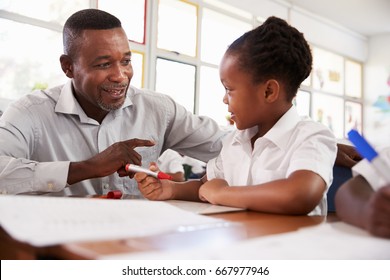 Teacher helping elementary school girl at her desk, close up