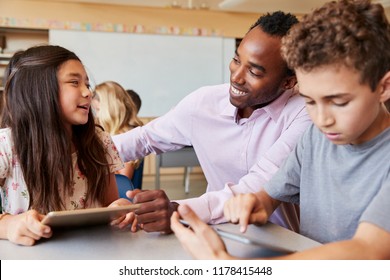 Teacher Helping Elementary School Kids Using Tablet Computer