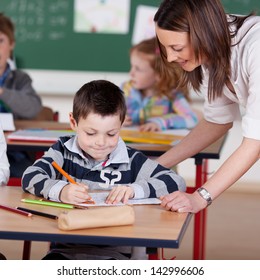 Teacher Helping Elementary Student At The Classroom