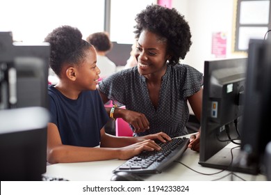 Teacher Helping Female High School Student Working at Screen In Computer Class