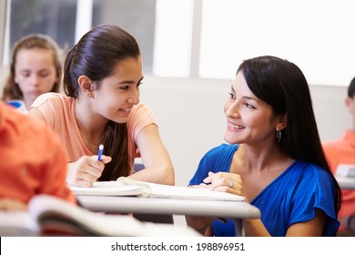 Teacher Helping Female High School Student In Classroom