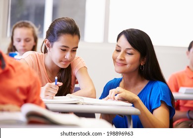 Teacher Helping Female High School Student In Classroom