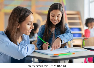 Teacher helping girl in classroom for knowledge, helping schoolgirl and teach her to draw. Education concept - Powered by Shutterstock