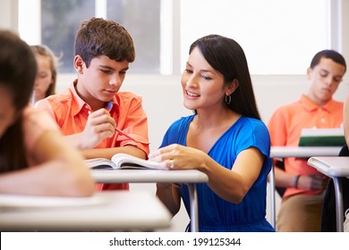 Teacher Helping Male High School Student In Classroom