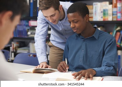 Teacher Helping Male Student In Classroom