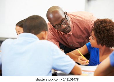 Teacher Helping Pupils Studying At Desks In Classroom - Powered by Shutterstock