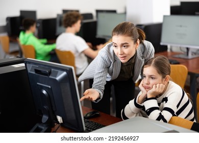 Teacher Helping Sad Young Girl To Solve Computer Problem During Lesson.