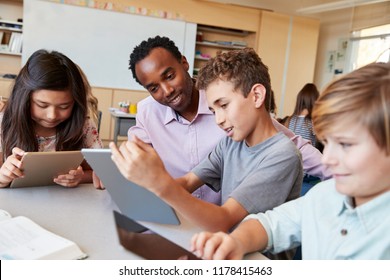 Teacher helping school kids using tablet computers in class - Powered by Shutterstock