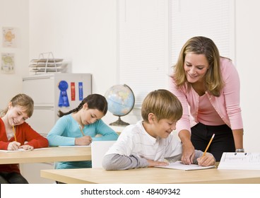 Teacher Helping Student In Classroom