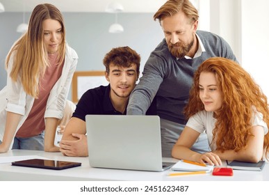 Teacher helping students in classroom. Male lecturer pointing at laptop screen and showing something to group of college students. Education, high school, technology and people concept. - Powered by Shutterstock