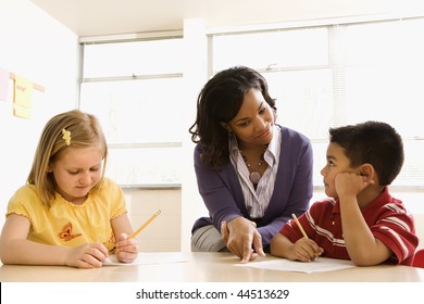 Teacher helping students with schoolwork in school classroom. Horizontally framed shot. - Powered by Shutterstock