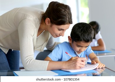 Teacher helping young boy with writing lesson - Shutterstock ID 107801354
