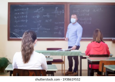 Teacher and his students wearing protective face mask in the classroom. Social distanting and classroom safety during coronavirus epidemic