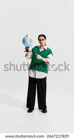 Teacher holding globe and pointer while explaining geography lesson with confident posture. Concept of educational demonstration, school subject, global awareness, teaching profession.