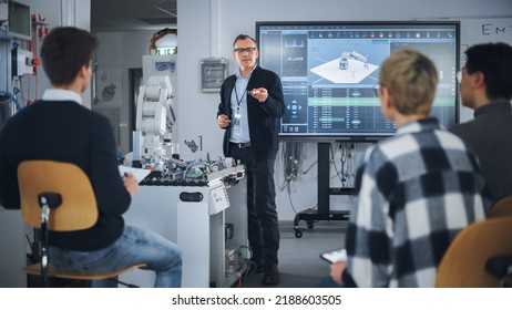 Teacher Holding Microchip For Futuristic Equipment During The Lesson While Robotic Arm Moving Nearby. Diverse Group Of Young Engineers Sitting At University. Computer Science Education Concept