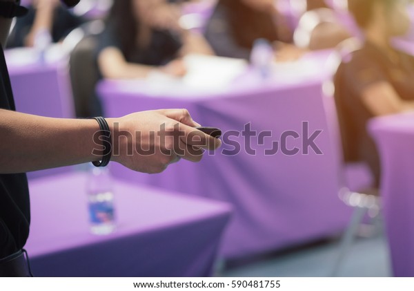 A\
teacher is holding remote control in his hand and teaching students\
in classroom in selective focus with warm fall\
color.