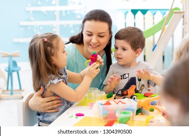 Teacher with kids working with plasticine at kindergarten or playschool