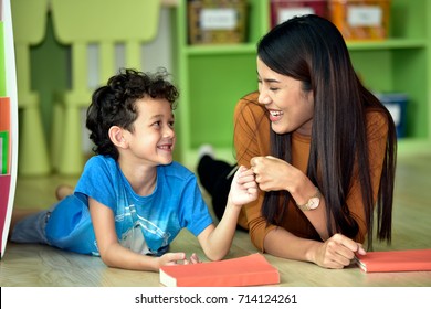 Teacher and kindergarten student having fun on learning in an international school library.teacher ,education, kid and primary school concept .