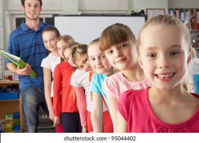 Teacher With Line Up Of Children In Class