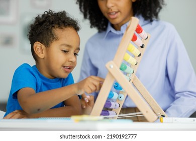 Teacher and little cute boy sitting at desk doing math using abacus doing homework early education - Powered by Shutterstock