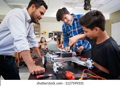 Teacher With Male Pupils Building Robotic Vehicle In Science Lesson