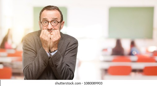 Teacher Man Using Glasses Terrified And Nervous Expressing Anxiety And Panic Gesture, Overwhelmed At Classroom