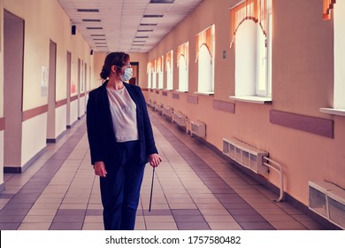 A Teacher In A Medical Mask Stands In An Empty School Corridor. Problems Of Education In The Quarantine Because Of The Epidemic Of The Coronavirus