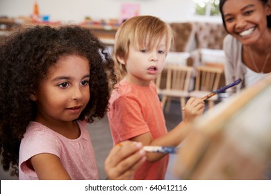 Teacher At Montessori School Helping Children In Art Class